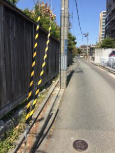 Black and yellow guy wire guards installed beside a roadside utility pole