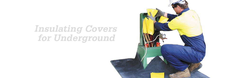 Worker installing yellow insulating covers on underground electrical equipment while using an insulating mat