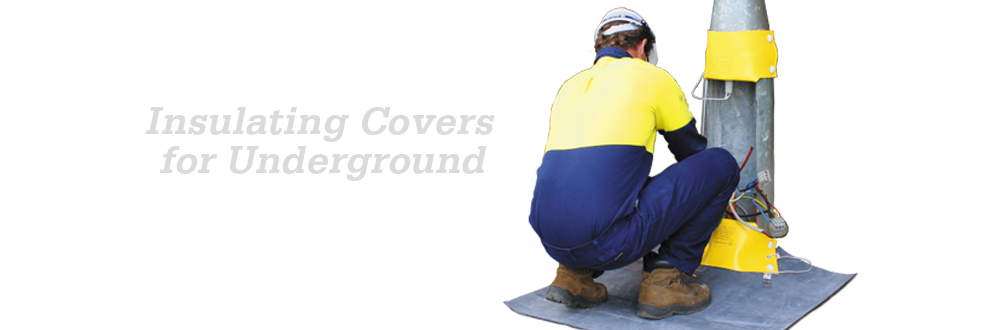 Worker fitting yellow insulating covers to underground electrical equipment while kneeling on an insulating mat